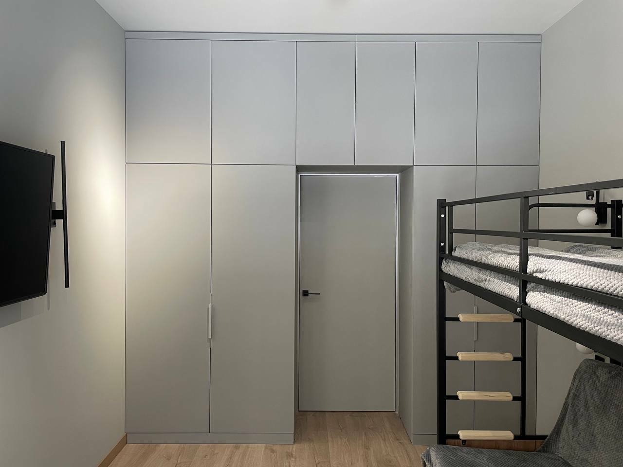 Серый распашной шкаф из МДФ с антресолью, установленный в спальной вокруг дверного проема, на заказ
